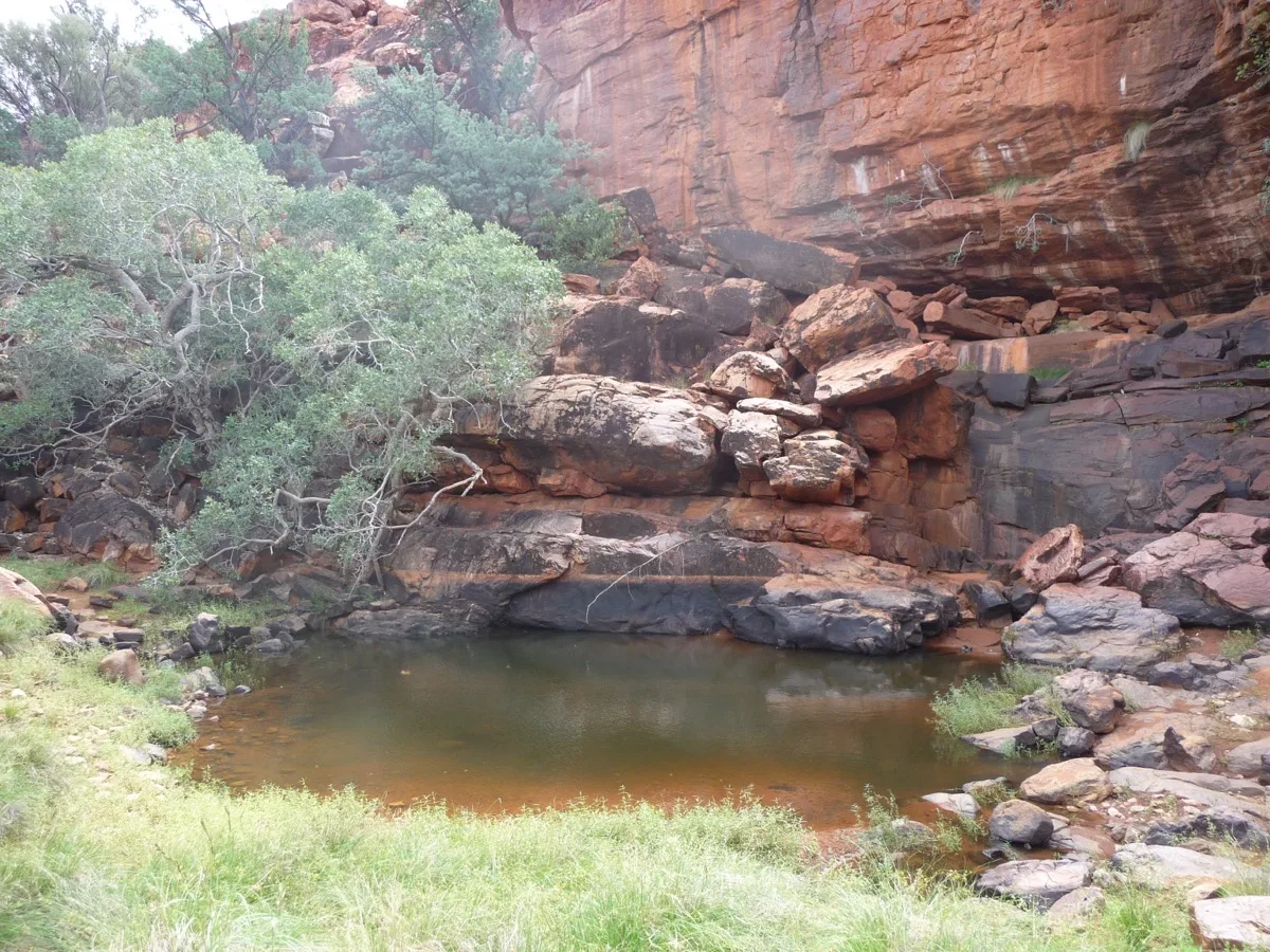 Peaceful desert pool surrounded by dramatic rock layers