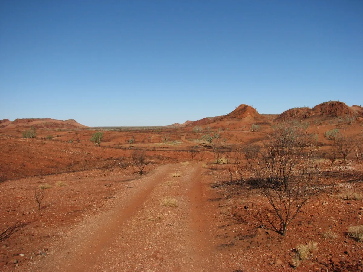 Remote red dirt track winds through spectacular outback country