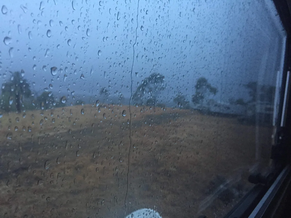 Raindrops clinging to the window, a sign of the day ahead.