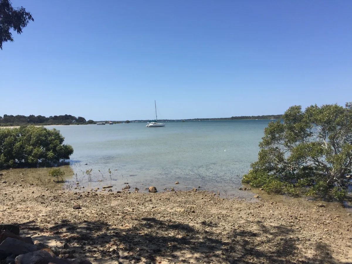 A sailboat rests in the clear waters of Tin Can Bay. The calm is almost palpable.