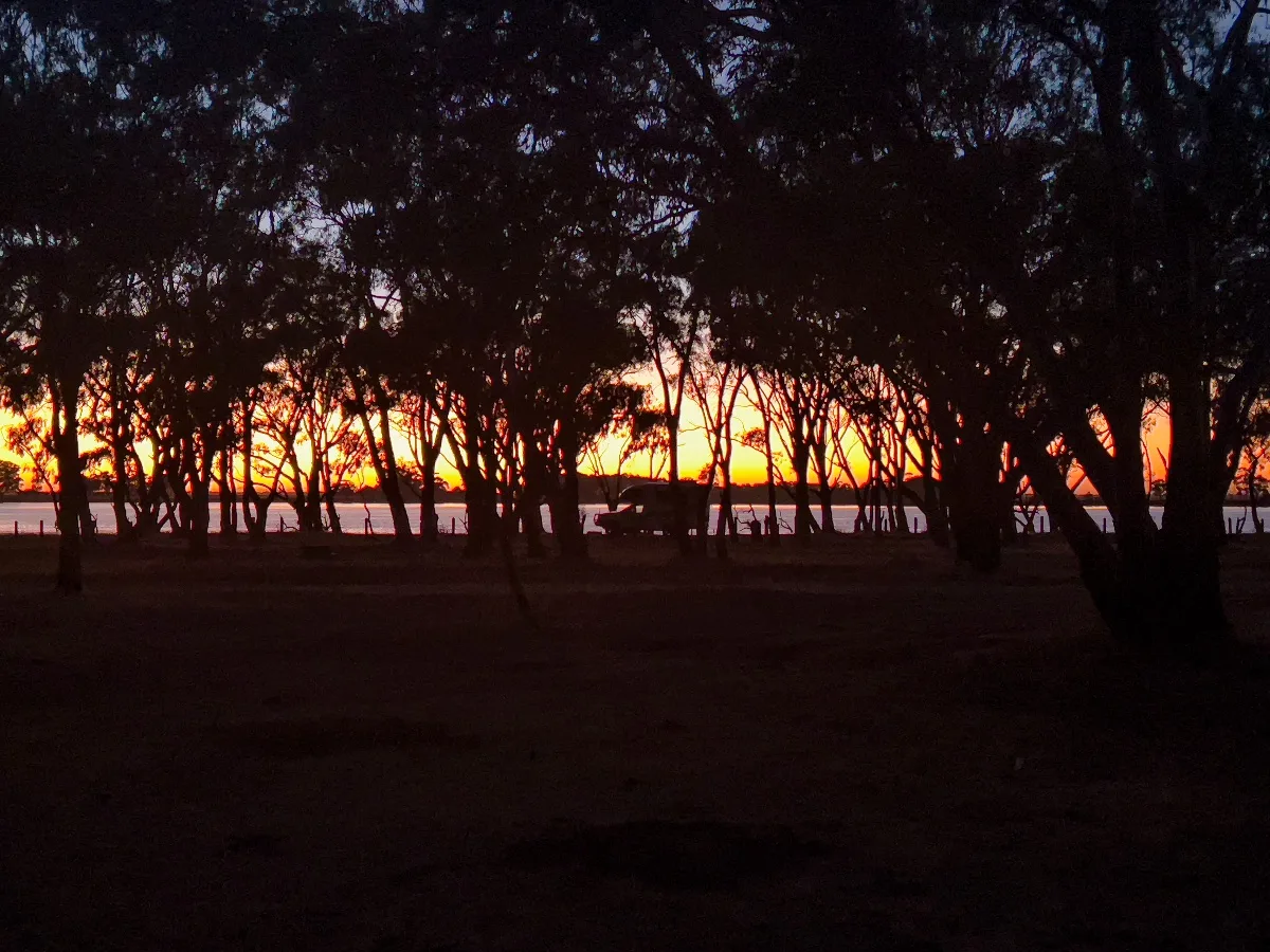 The fiery sunset over Taylors Lake as seen through the trees surrounding the camping grounds.