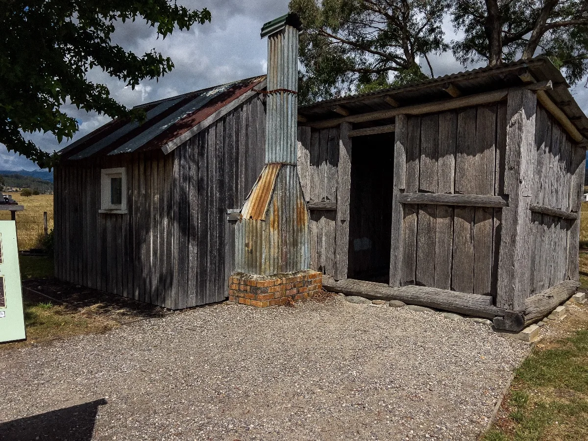 The weathered timber walls and corrugated iron chimney of the historic pioneer hut.