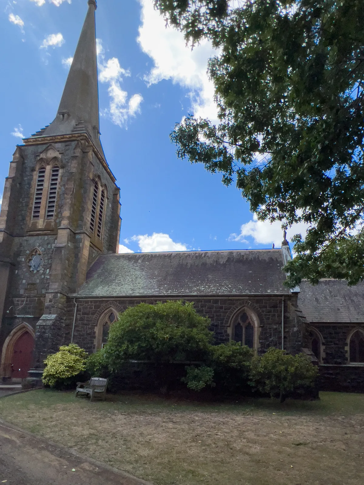 The bluestone exterior of St Mary’s Church features arched windows and a slate roof weathered by time.