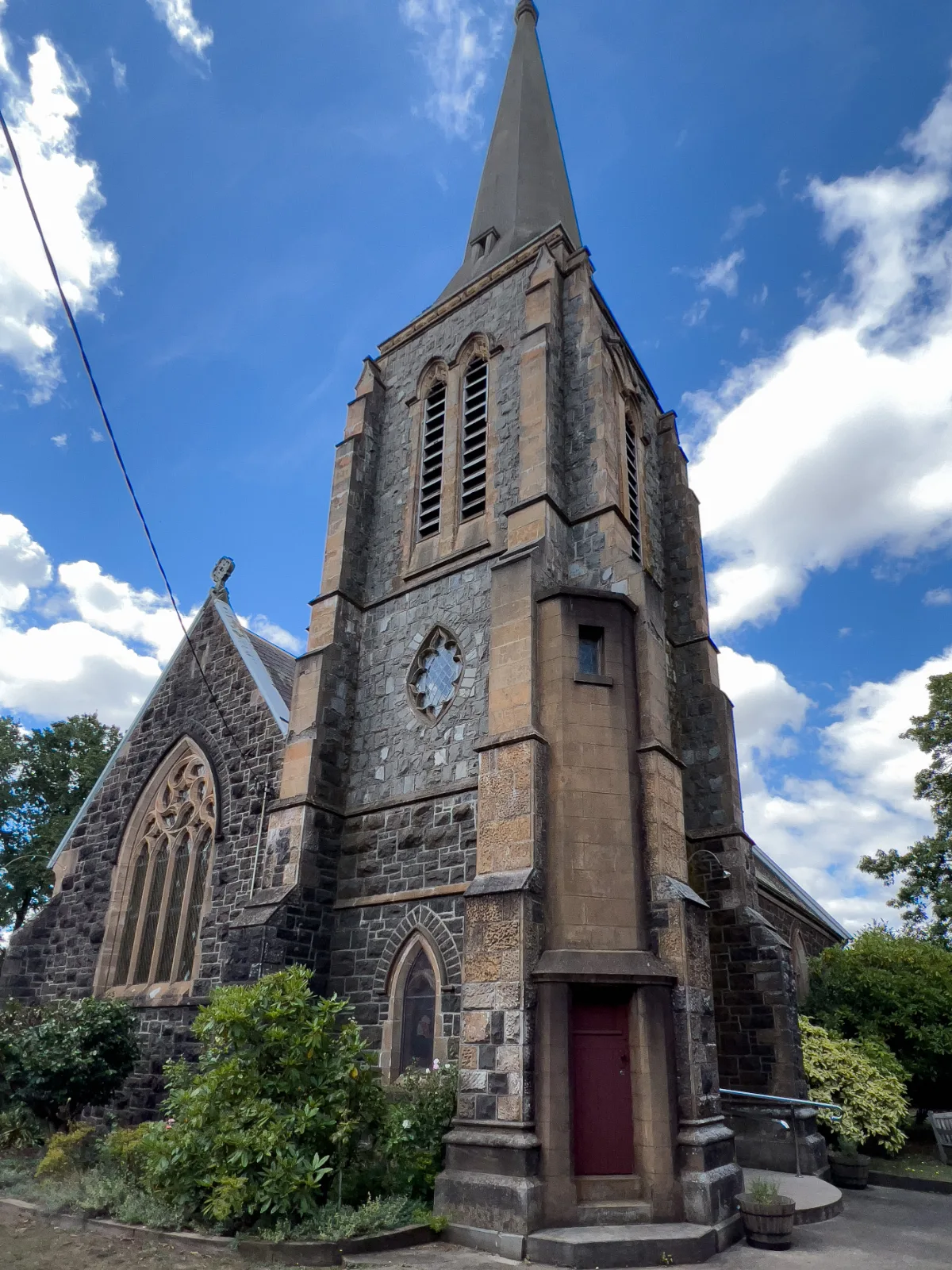 The impressive stone spire and belfry tower of the church stand tall against the drifting white clouds.