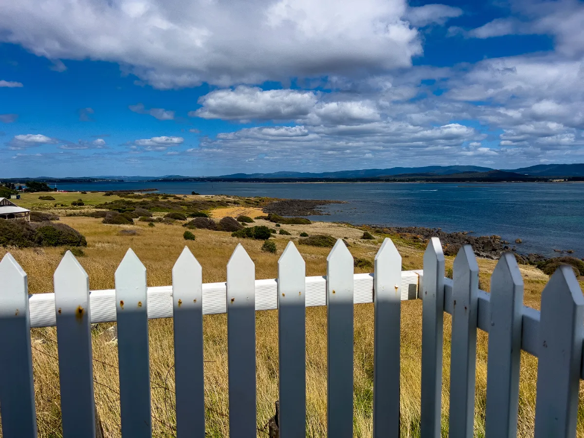 Looking out over the water towards the mountains, a perfect view framed by a white picket fence.