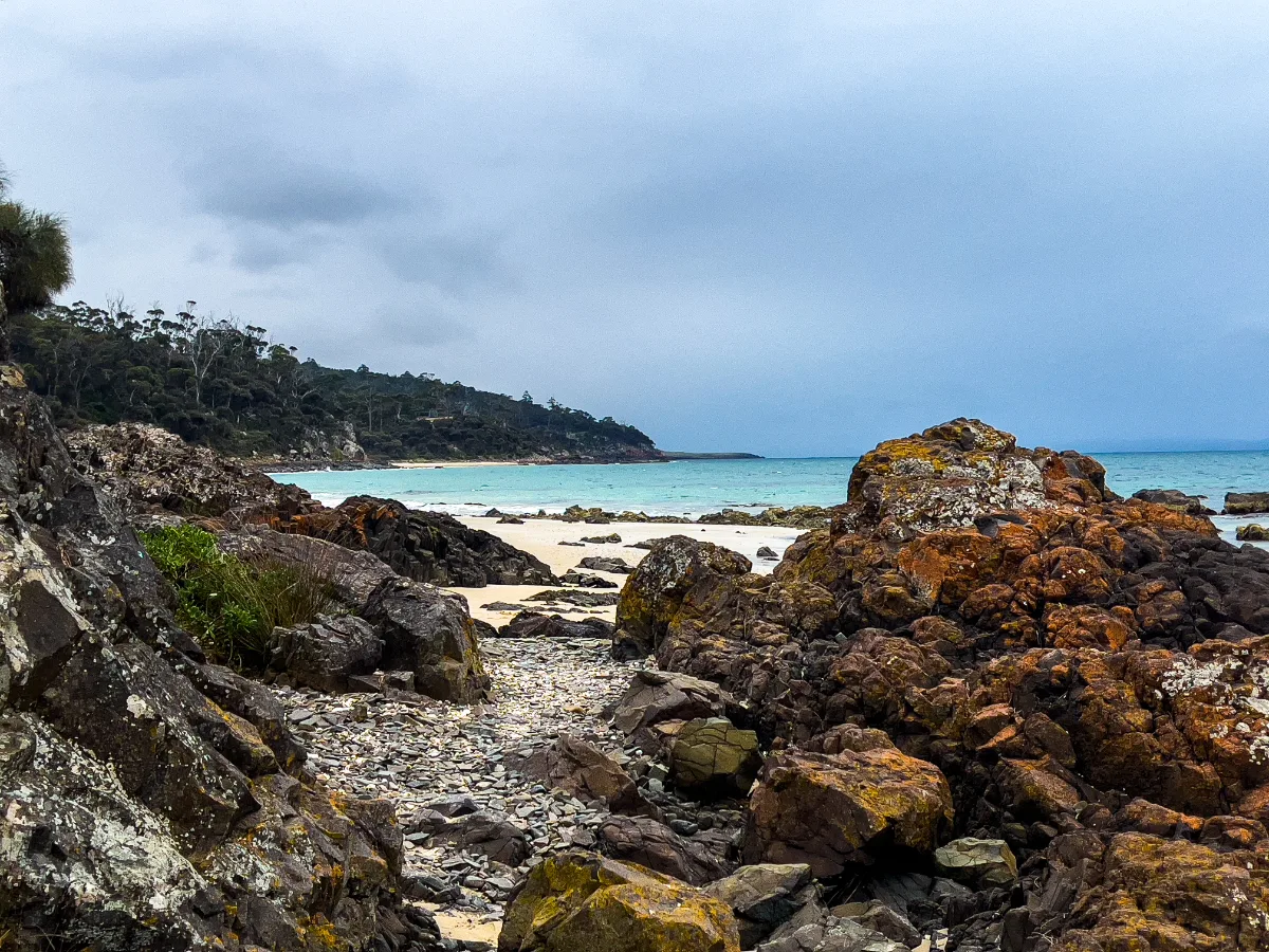Vibrant orange rocks and crystal-clear water along the coast—the perfect spot for a quick breath of fresh Tassie air.