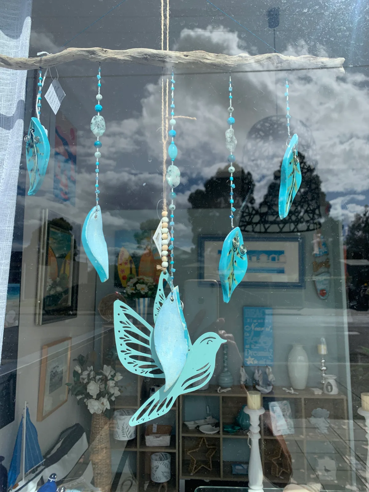 A beautiful turquoise bird mobile catching the light in a local window display.