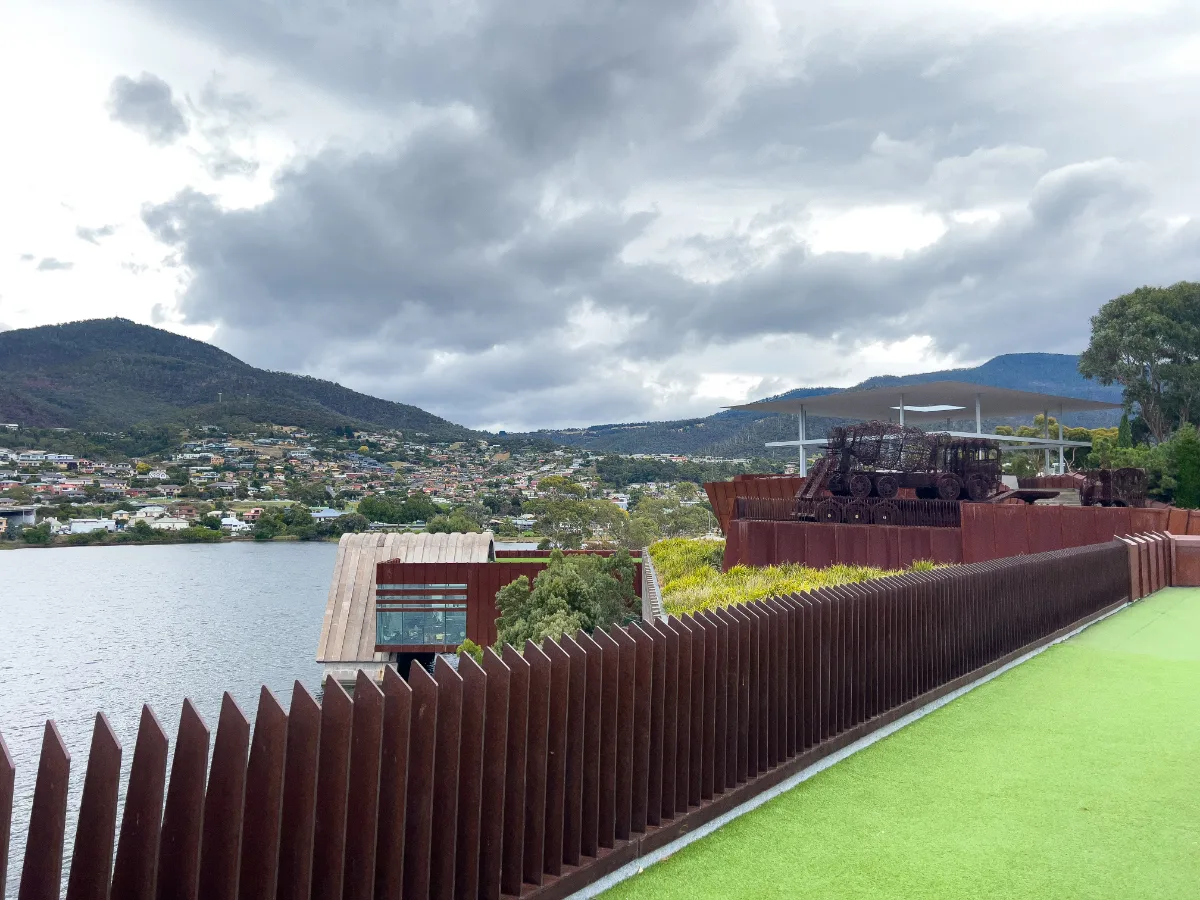 The view across the water from the MONA grounds, with the rusted steel fences and the mountains in the distance.