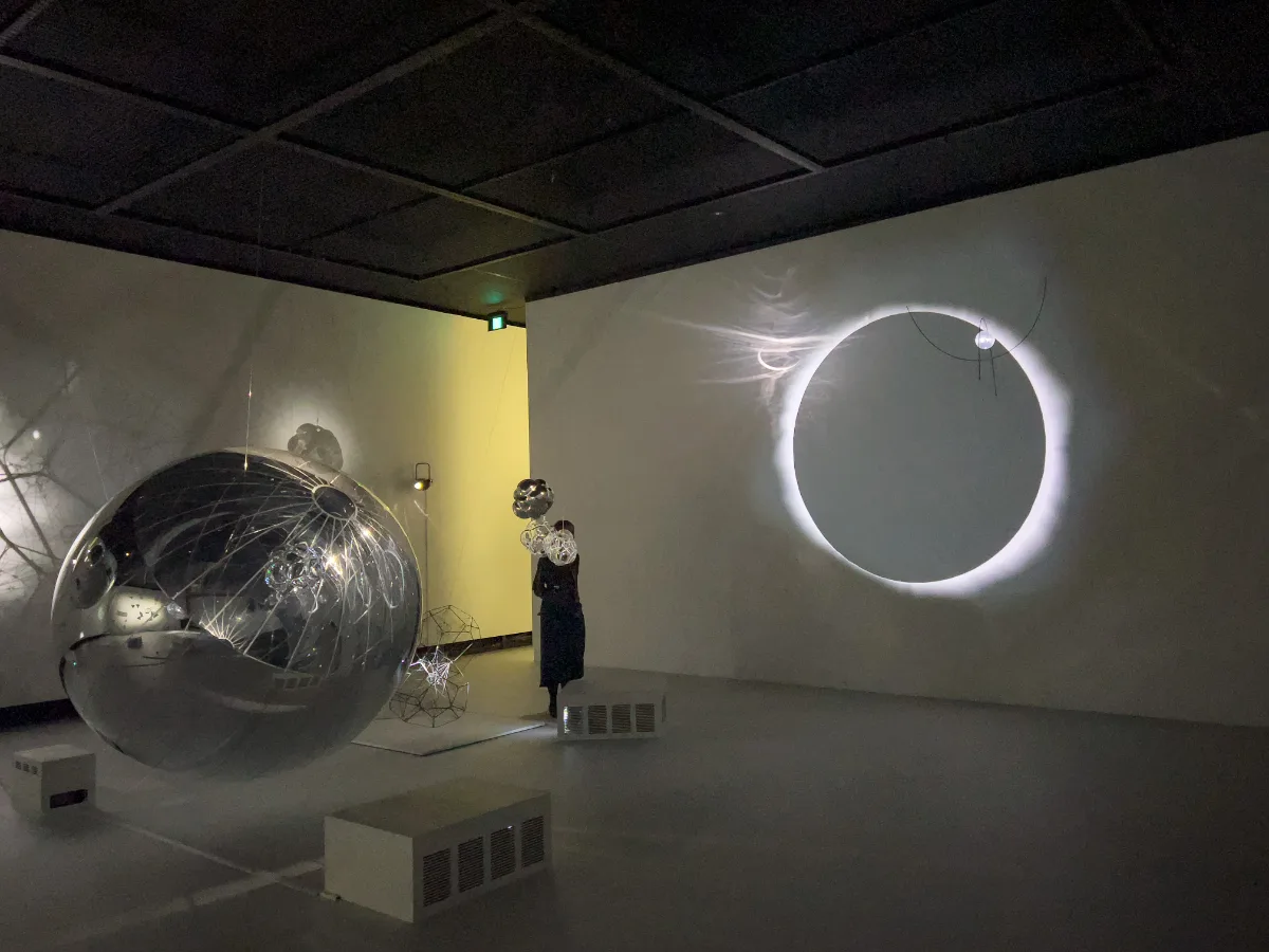 A silver orb and a projected eclipse creating a very quiet, moody moment in the dark.