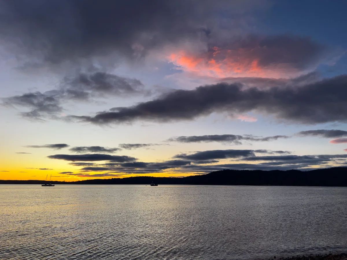 The morning light catching a solitary pink cloud as the sun begins to lift over the Tasmanian hills.
