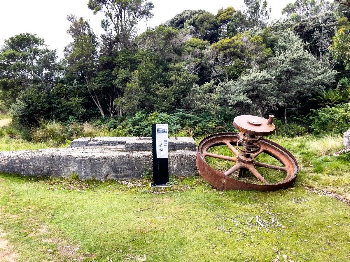 A massive rusted iron wheel and old concrete footings marking the history at Cockle Creek.