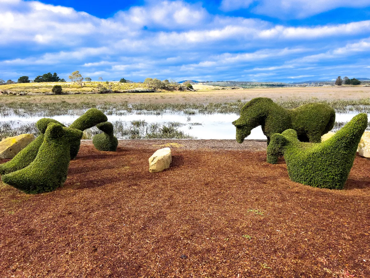 Whimsical topiary bushes shaped like a horse and birds overlooking the lake.