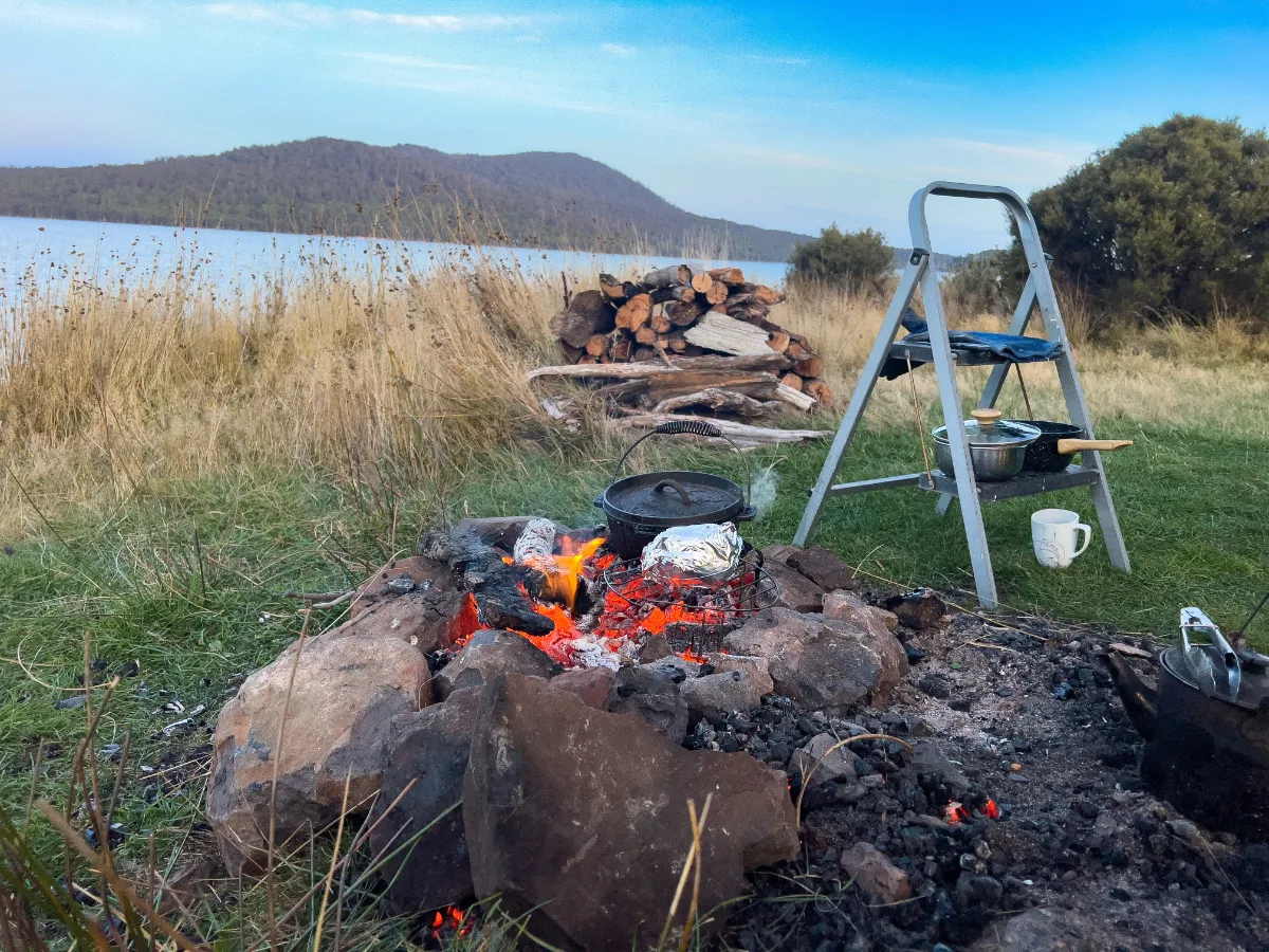 Our highland kitchen in action, with the camp oven on the coals and the ladder doing double duty as a pantry shelf.