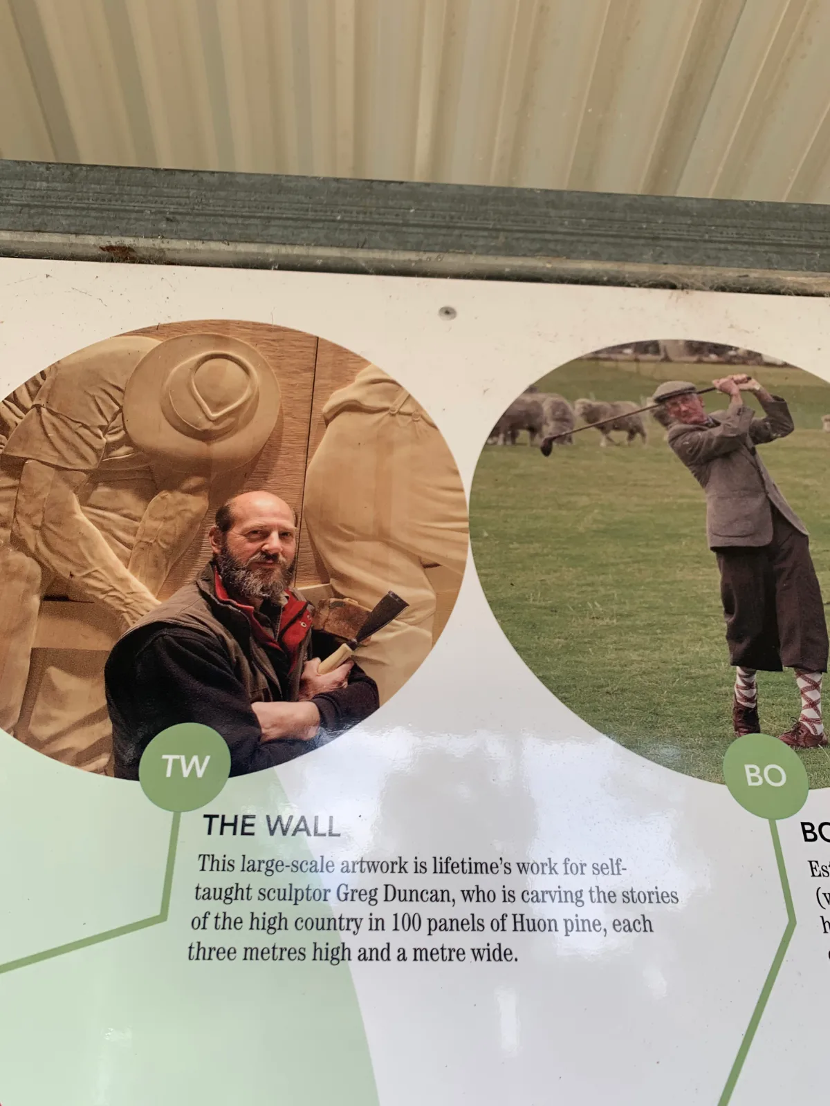 An info board showing the artist, Greg Duncan, at work on his massive 100-metre Huon pine mural.