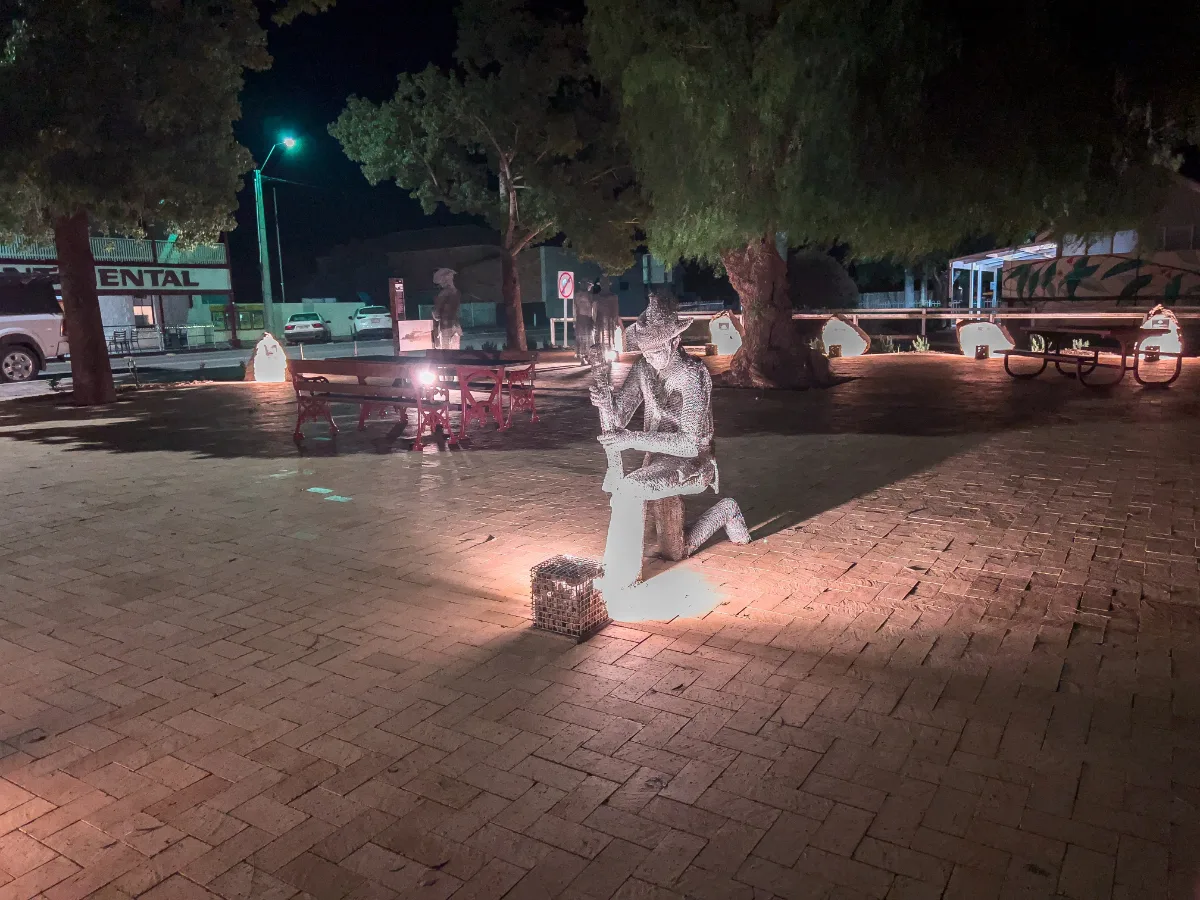 The war memorial sculptures illuminated at night.
