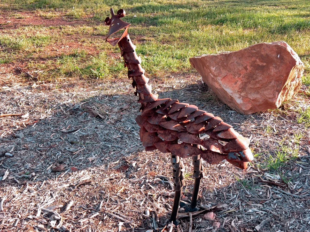 An emu sculpture, seemingly made from recycled metal, adds a touch of whimsy to the walking trail.