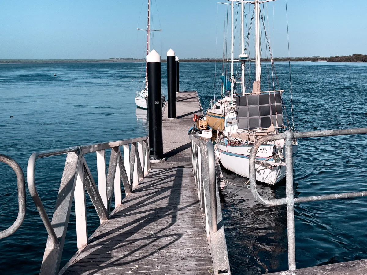 Sailboats moored at the local jetty, swaying gently in the clear, calm waters.