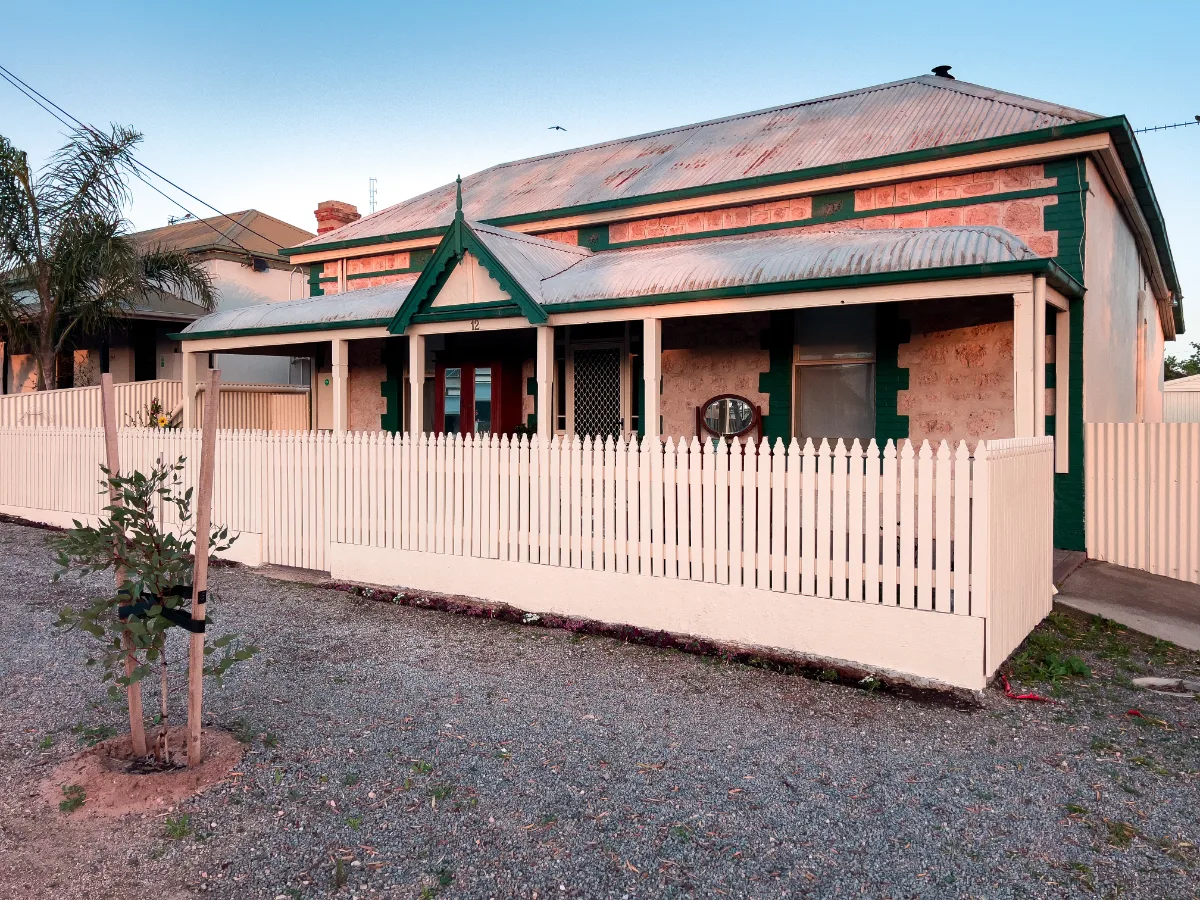 A well-maintained sandstone home in Wallaroo, its picket fence gleaming in the morning light.