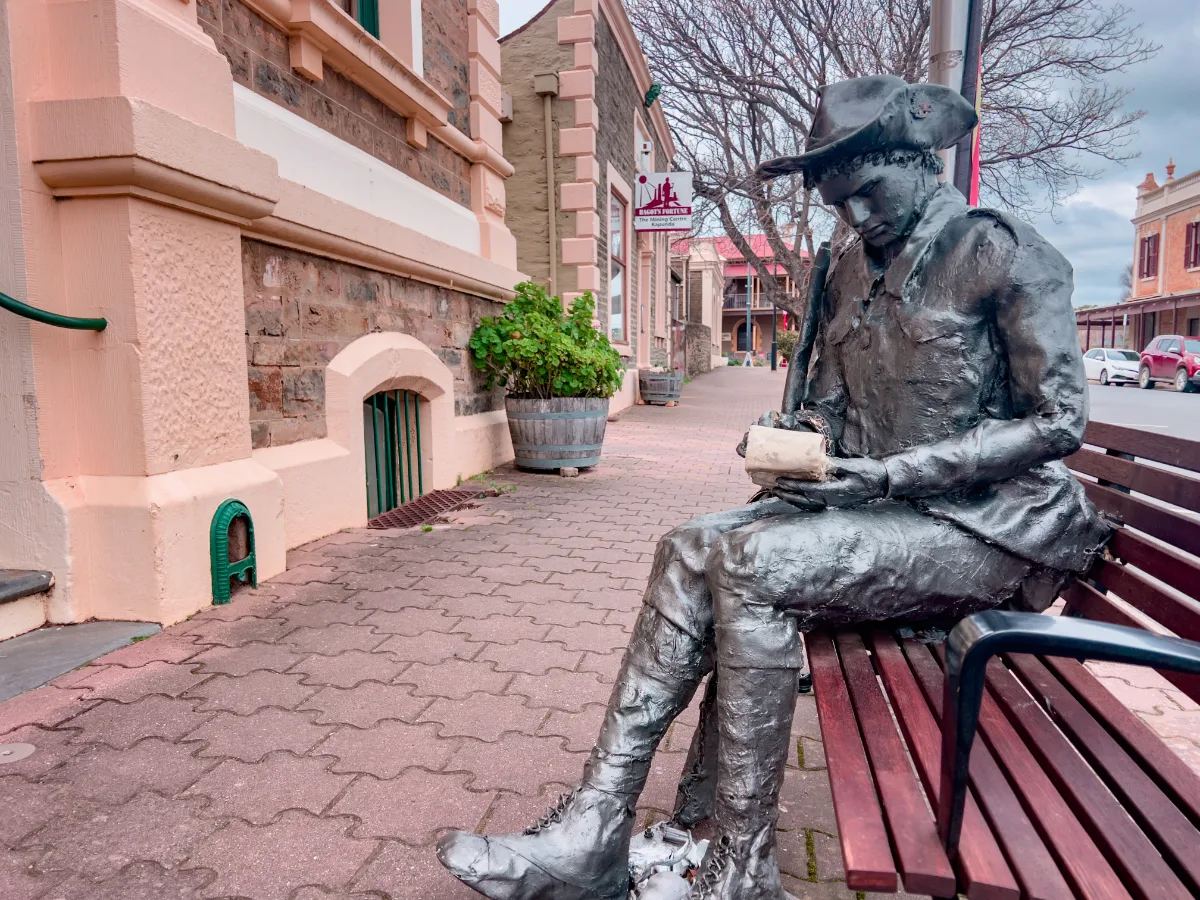 A life-size statue of Sir Sidney Kidman sits on a bench in Kapunda, forever immersed in his reading.