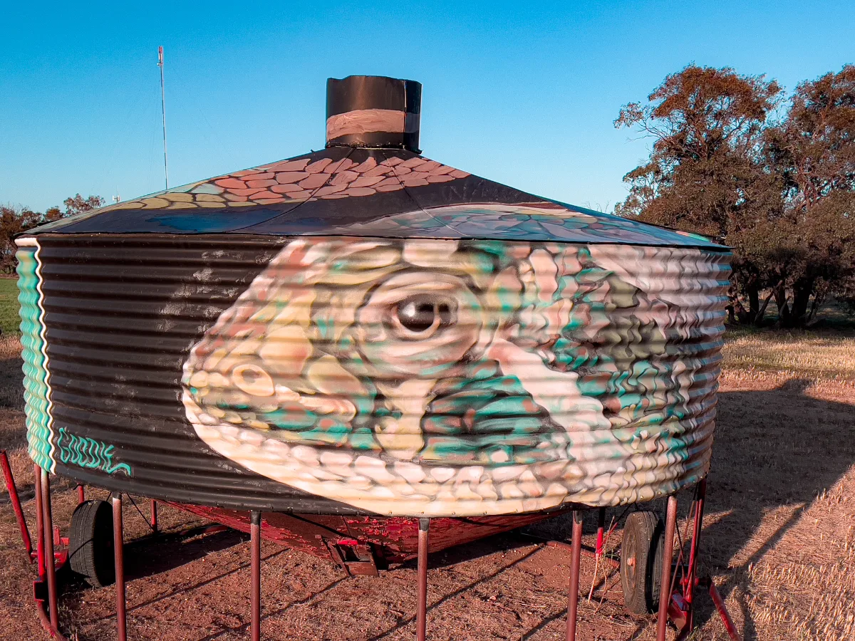 Vibrant street art transforms a grain silo into a canvas, showcasing a meticulously painted lizard.