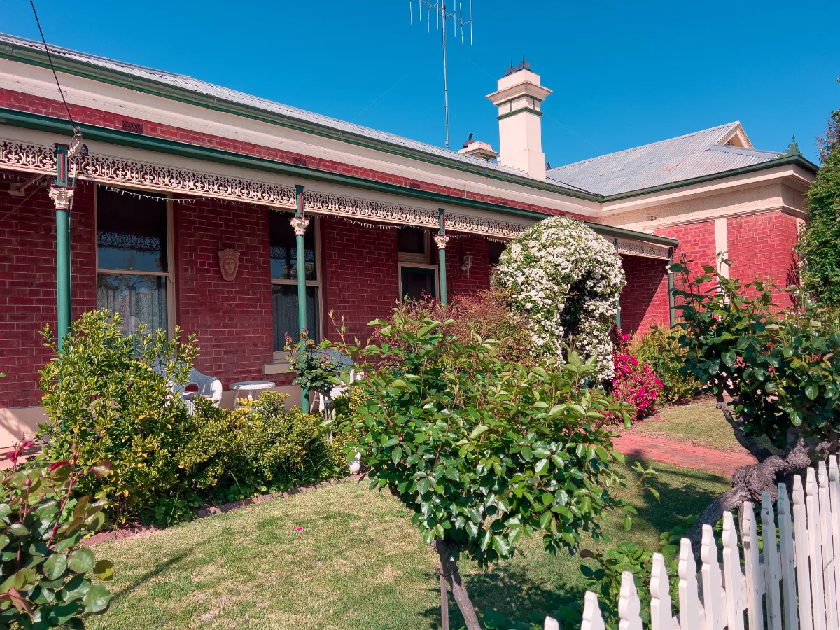 A well-maintained brick home in Tocumwal, featuring a flowering archway and intricate iron lacework.