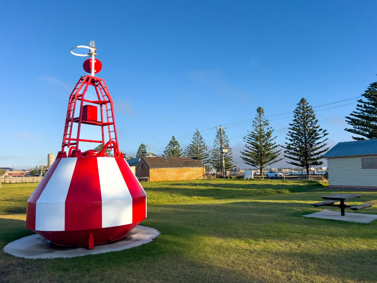 A retired navigational buoy stands as a landmark in Port Albert, a reminder of the town's maritime history.