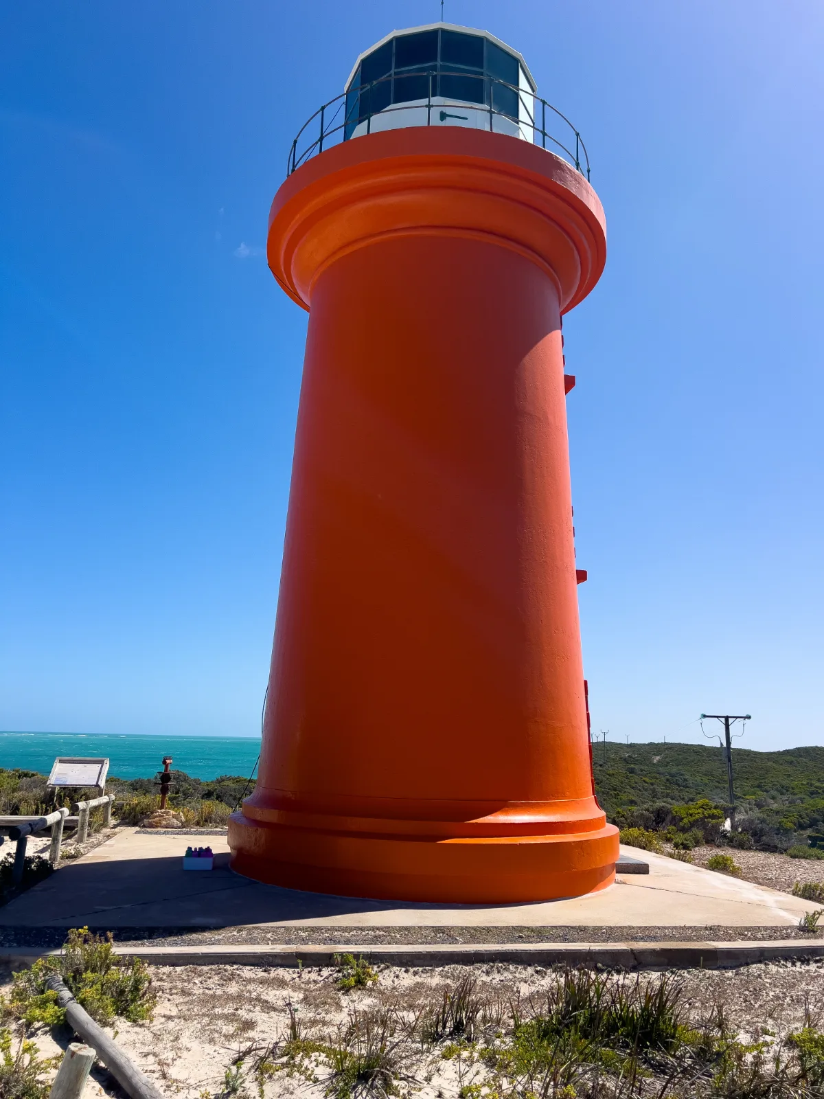 The bright orange Carpenter Rocks lighthouse, a striking contrast to the azure sky.