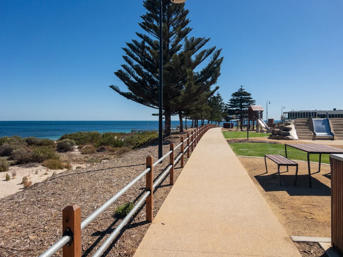 A picturesque walking path runs alongside the beach, offering stunning coastal views.