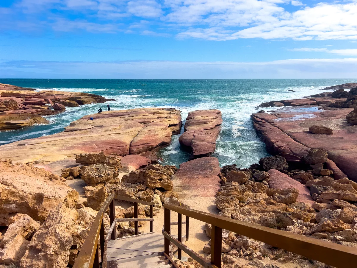 A staircase descends toward the ocean at Woolshed Cave, offering a dramatic view of the rugged coastline.