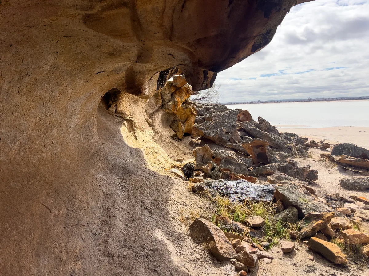 Peeking out from under a rock overhang reveals a picturesque view of the lake.