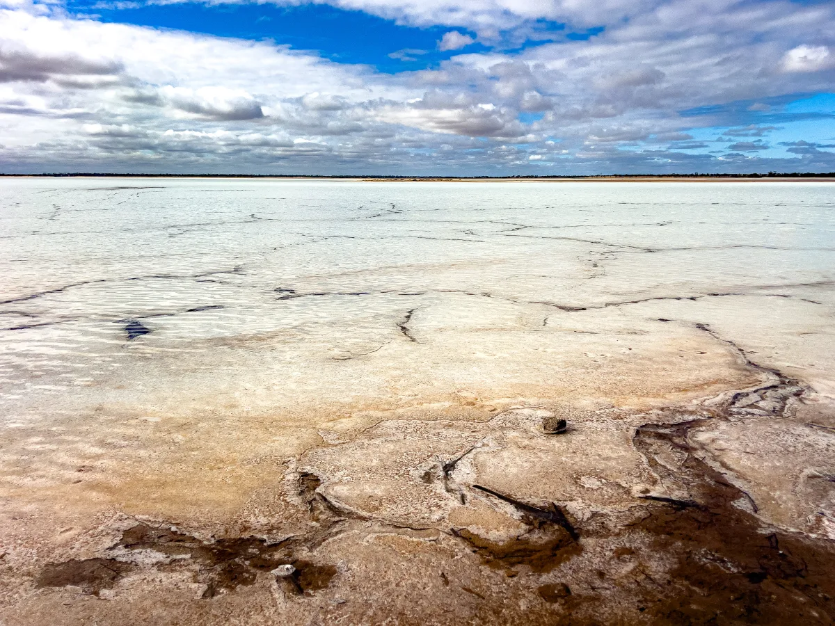The vast expanse of the salt lake near Eaglestone Rock shimmers under a partly cloudy sky.