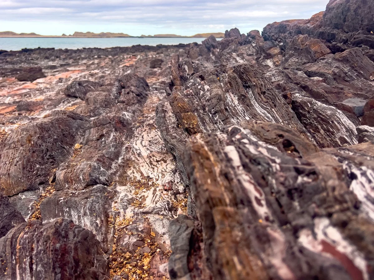 Layered coastal rocks meet tranquil waters along Australia's shore