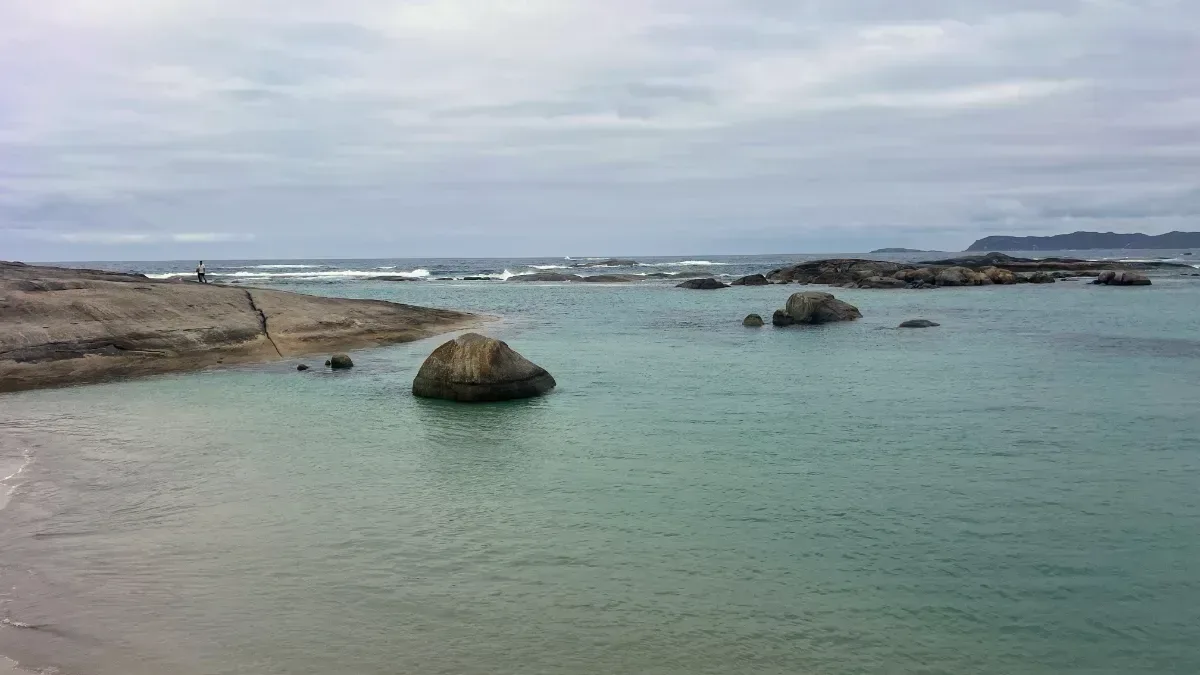 A tranquil vista of Greens Pool reveals the protected waters and striking granite outcrops that define this beautiful location.
